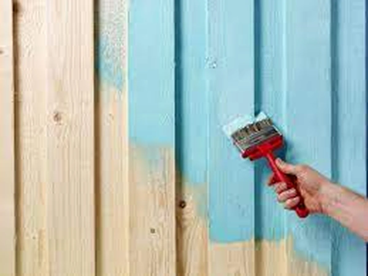 Fence painting in Cheltenham by Cheltenham Decorators, brush applying stain to wooden fence panels