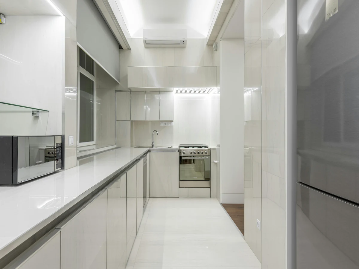 Narrow white kitchen with worktops along one wall