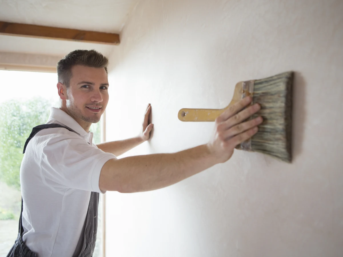 Decorator painting a large wall in Cheltenham, professional painting and decorating service