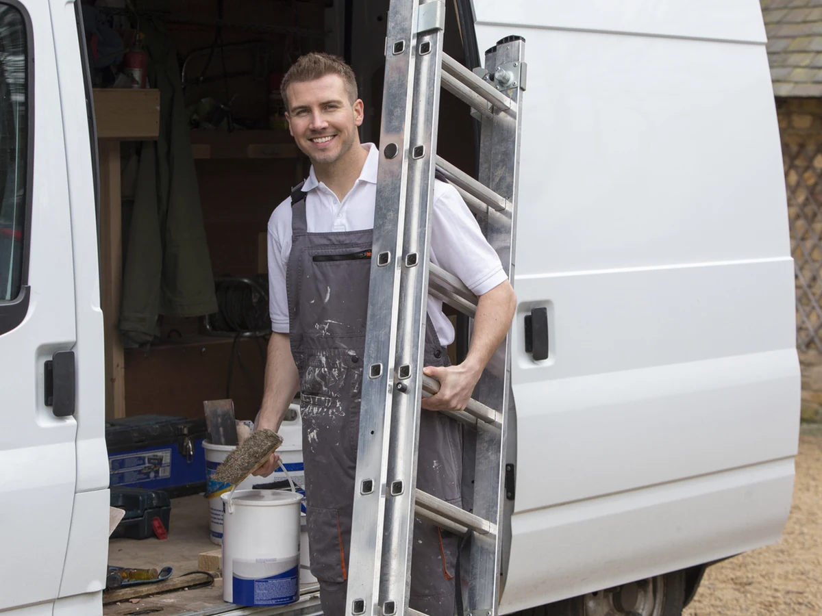 Smiling decorator on a ladder working at a Hucclecote property
